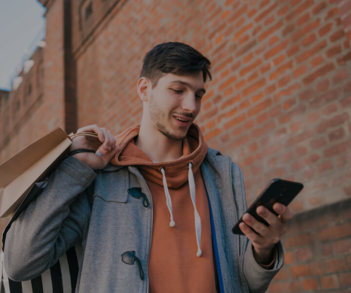 guy smiling with phone and shopping bags